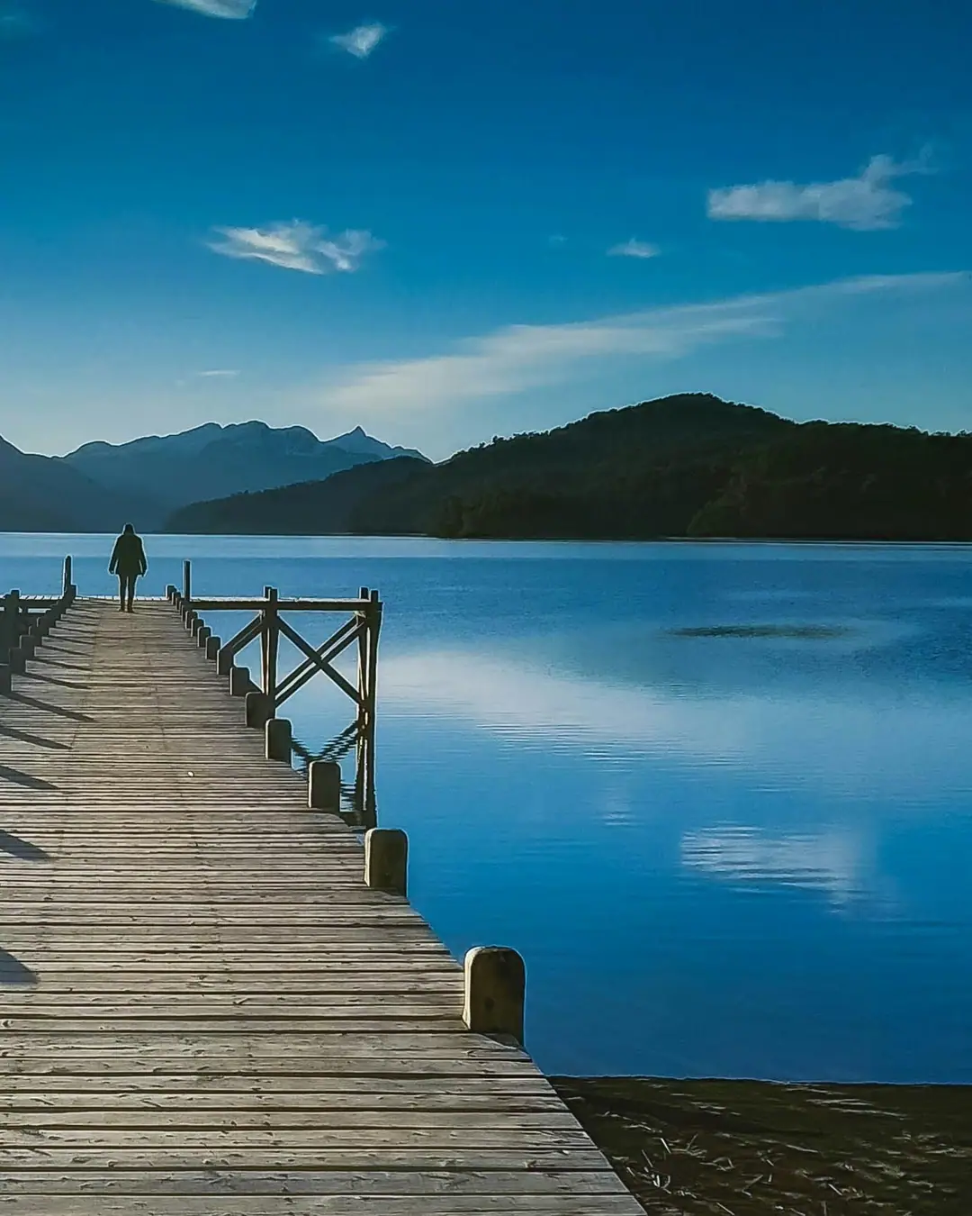 Muelle de madera sobre un lago de la Patagonia con montañas al fondo