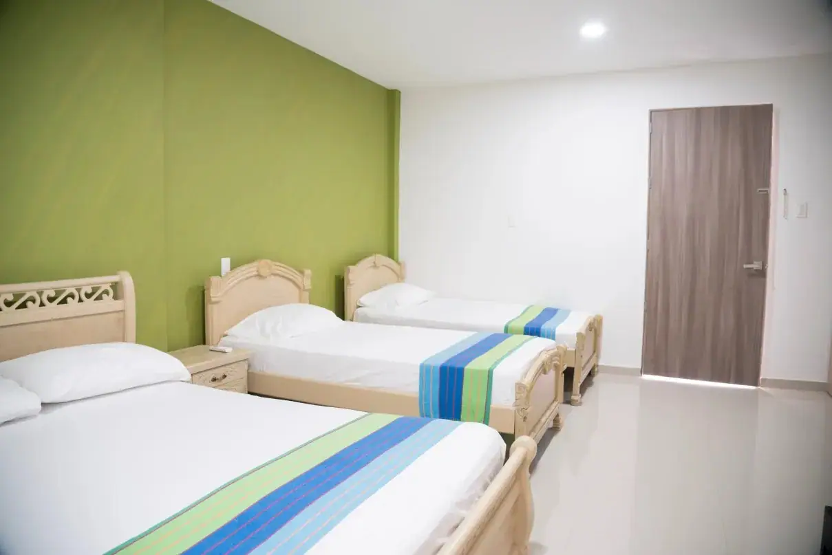 Habitación de Emerawaa con tres camas y pared verde