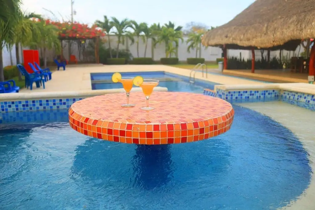 Mesa de baldosa dentro de la piscina con dos cocteles de maracuyá