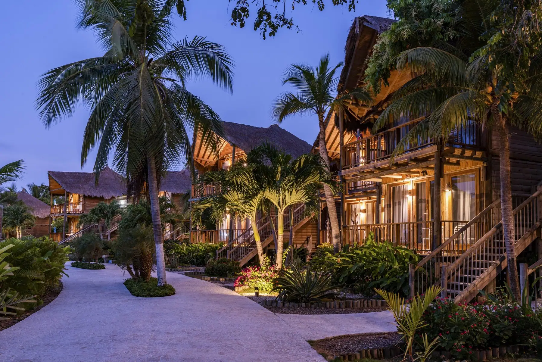 Bungalows de madera entre palmeras y jardines del hotel Isla del Encanto