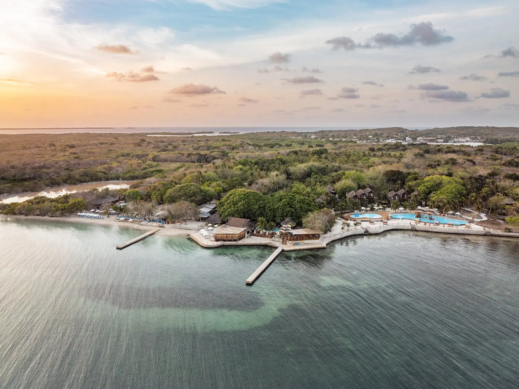 Vista aérea de la isla privada del hotel Isla del Encanto, con sus muelles, piscinas y el mar al atardecer