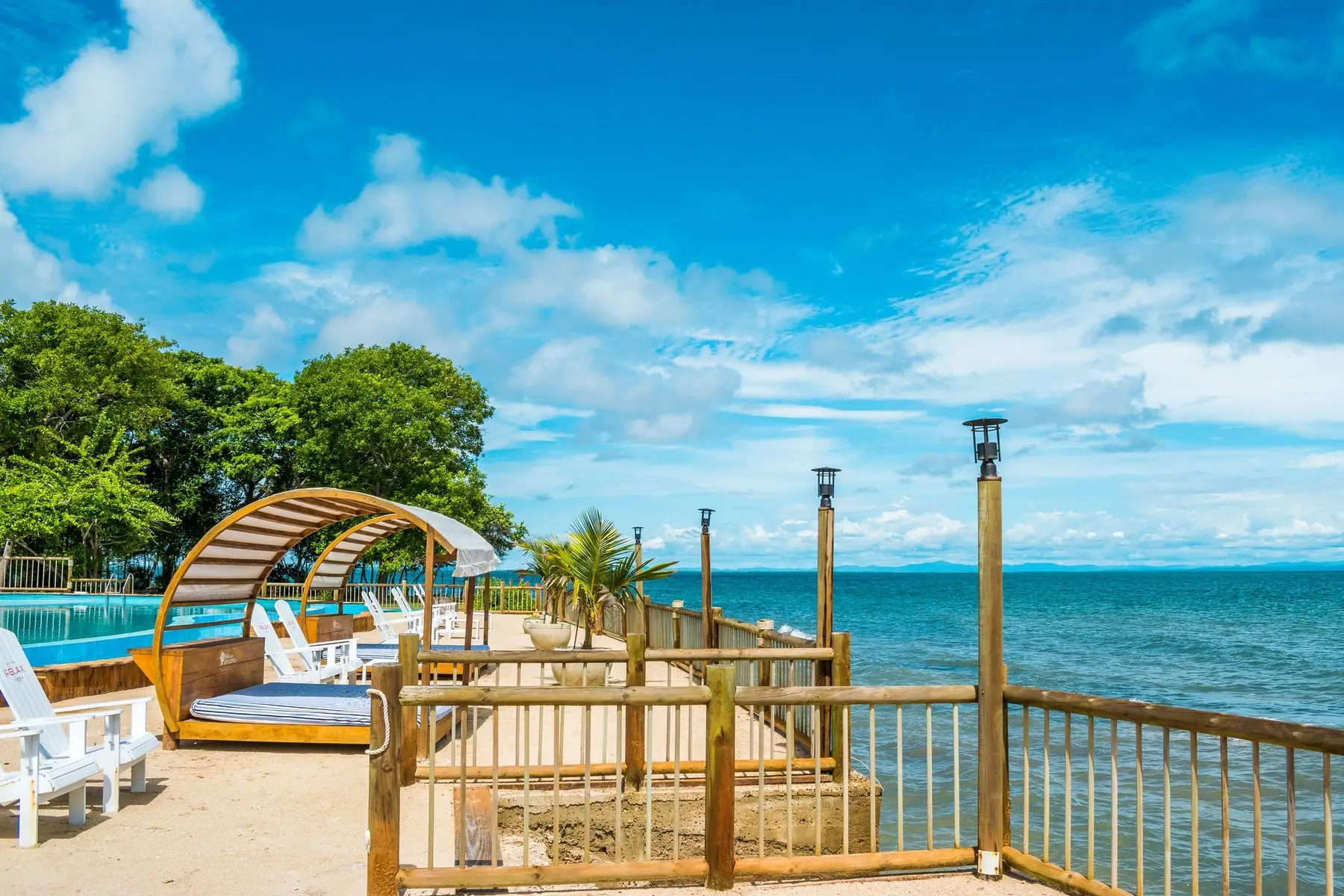 Terraza de madera con camas de playa frente al mar turquesa en Isla del Encanto