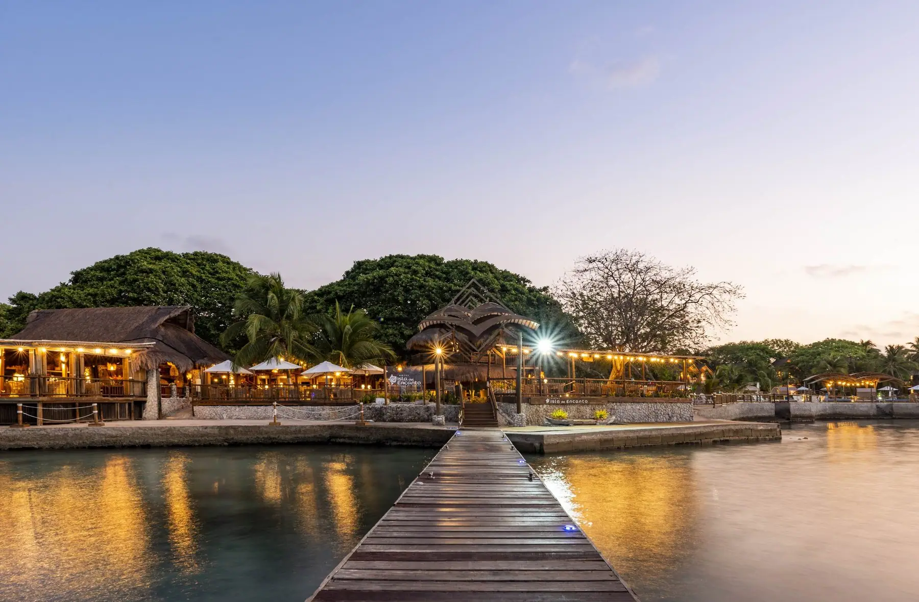Muelle de madera de la entrada del hotel Isla del Encanto iluminado al anochecer