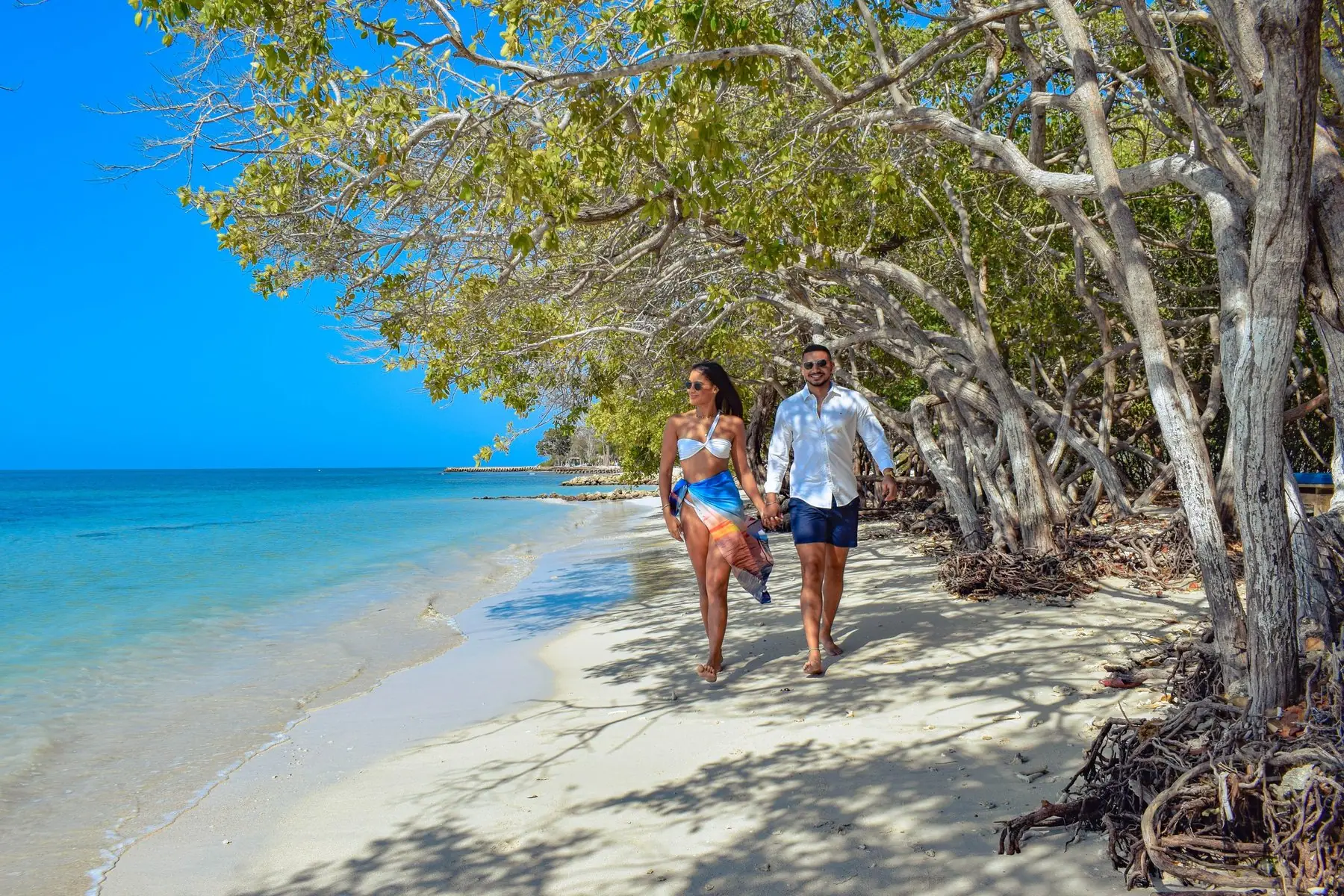 Pareja caminando de la mano por la playa de arena blanca de Isla del Encanto