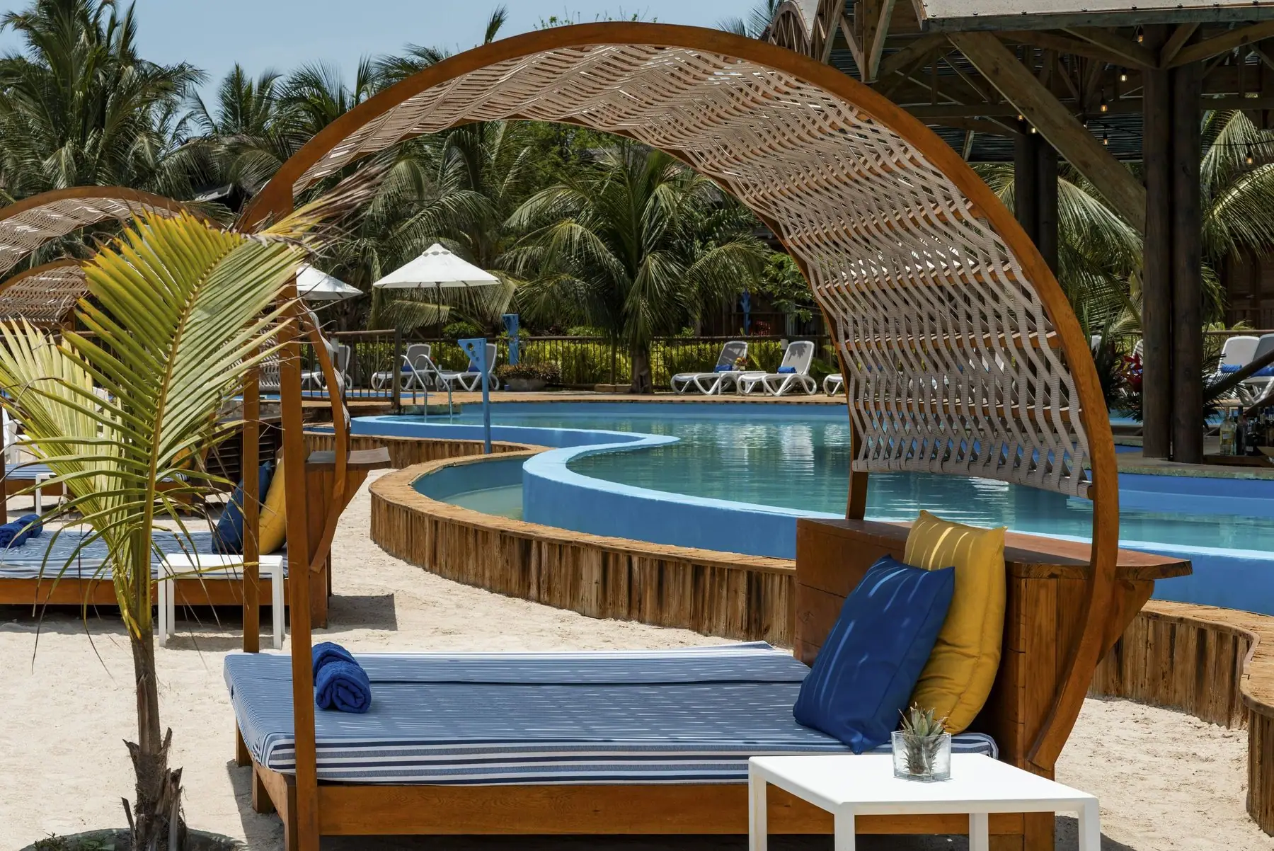 Cama de playa con techo de mimbre junto a la piscina de Isla del Encanto