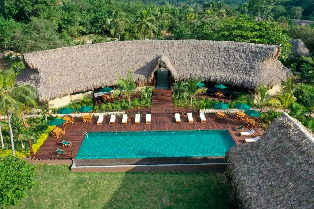 Vista aérea de la piscina y las cabañas de techo de palma de Senda Watapuy entre la selva
