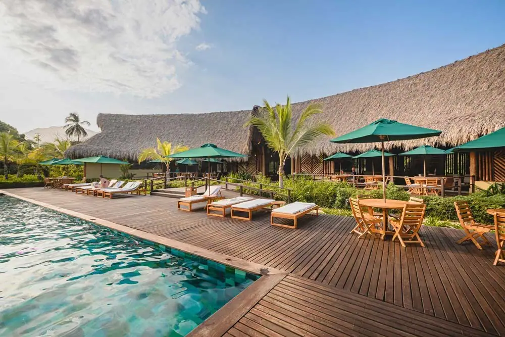 Piscina de Senda Watapuy con terraza de madera, sombrillas verdes y asoleadoras