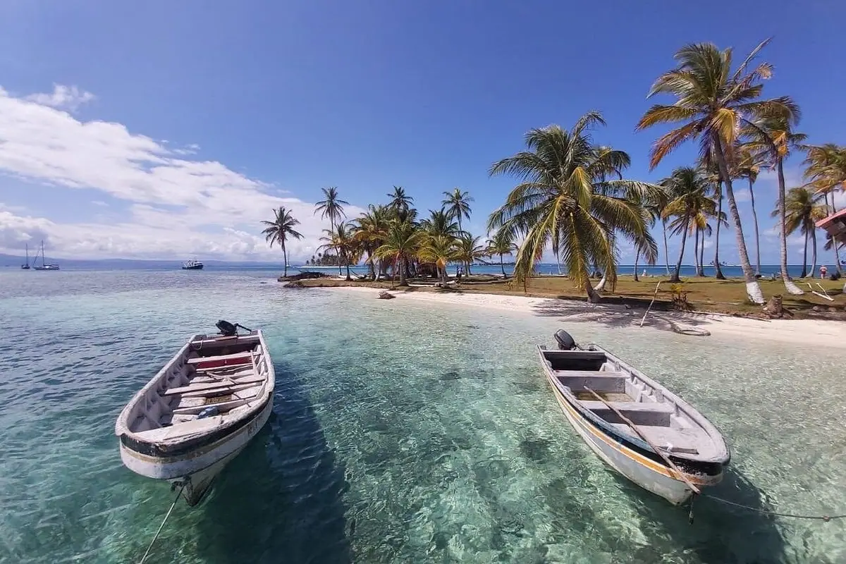 Lanchas sobre agua cristalina frente a una isla de palmeras en San Blas