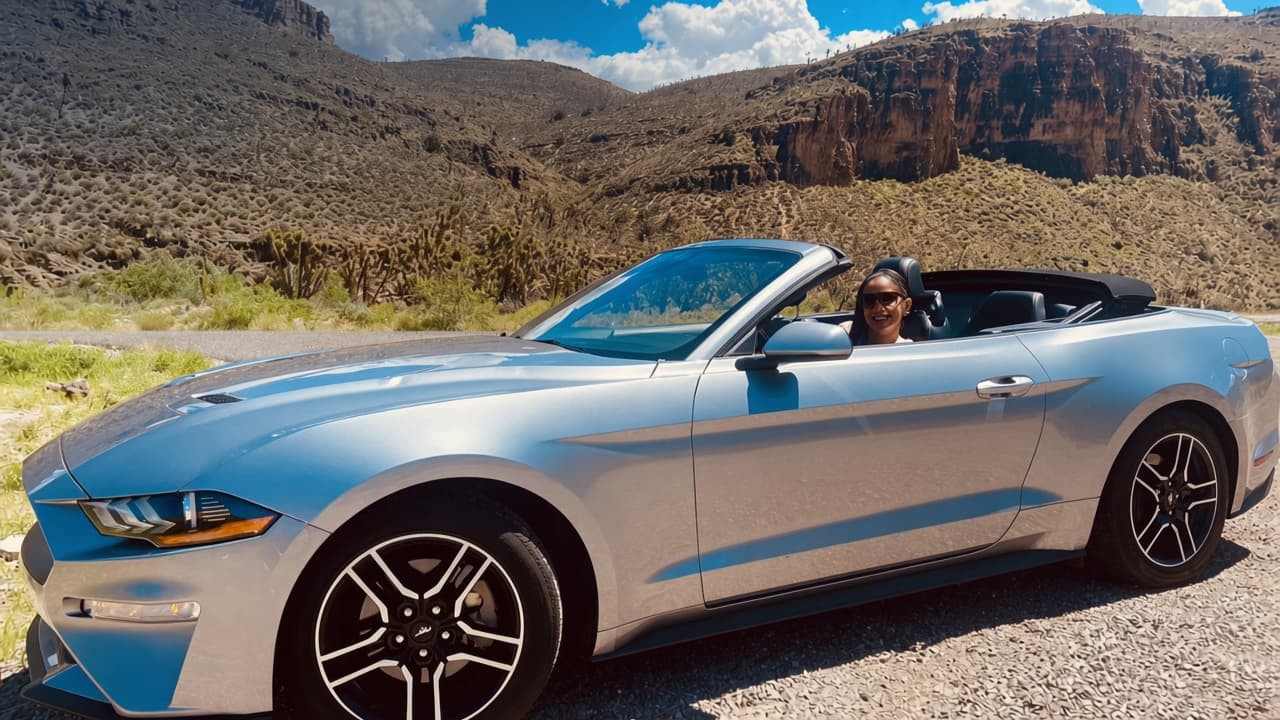 Convertible plateado en una carretera entre montañas