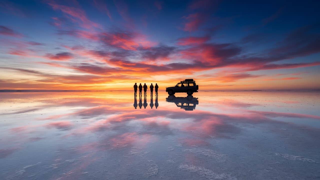 Viajeros reflejados en el Salar de Uyuni al atardecer