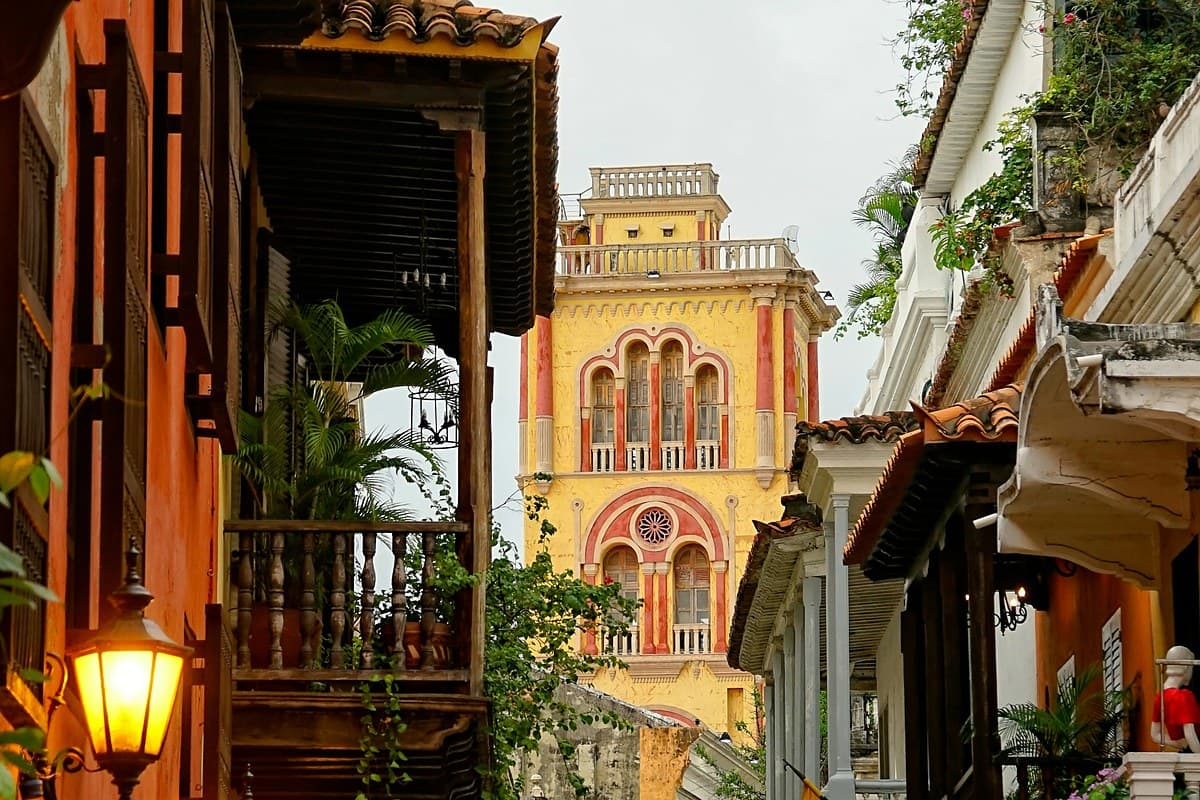 Calle colonial de Cartagena con balcones de madera y una torre amarilla al fondo