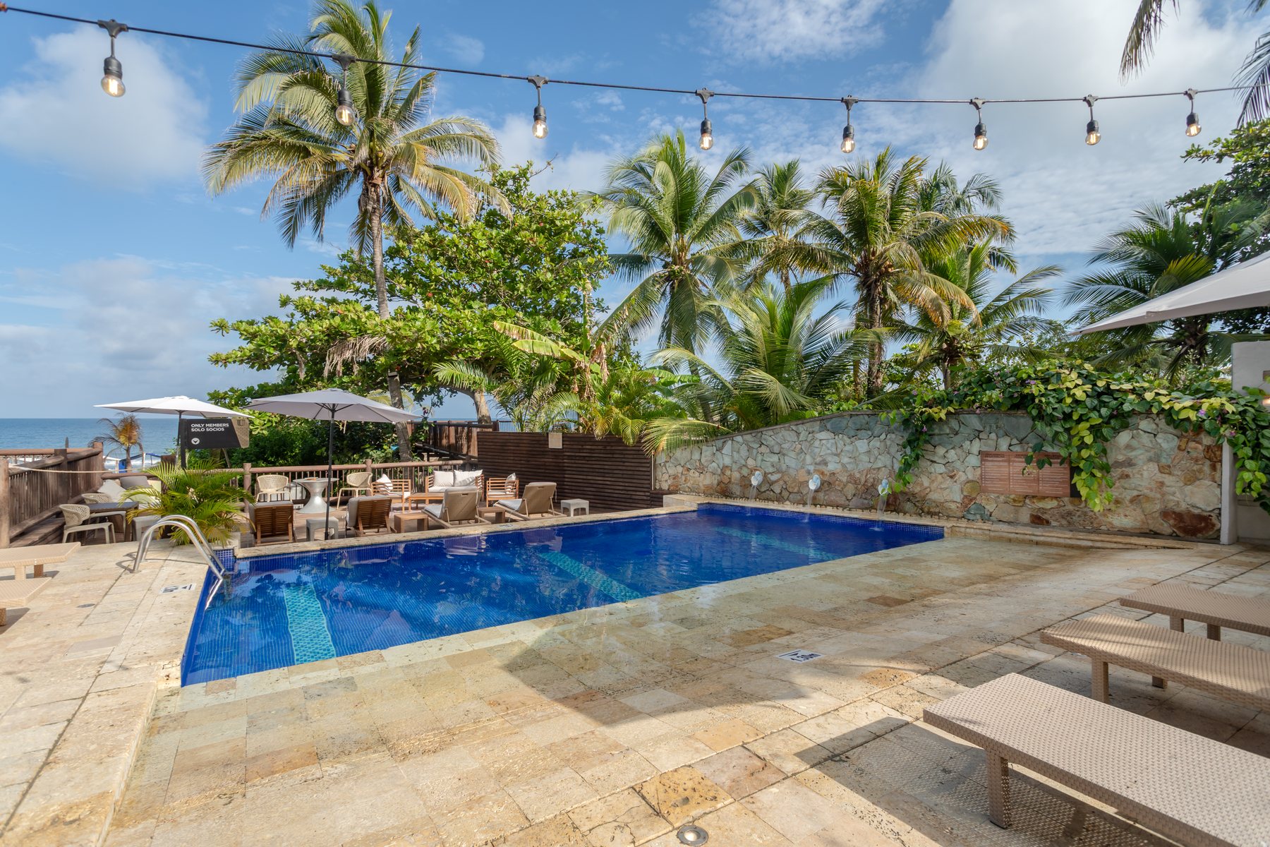 Piscina del club de playa del Grand Sirenis Cartagena con palmeras y el mar al fondo