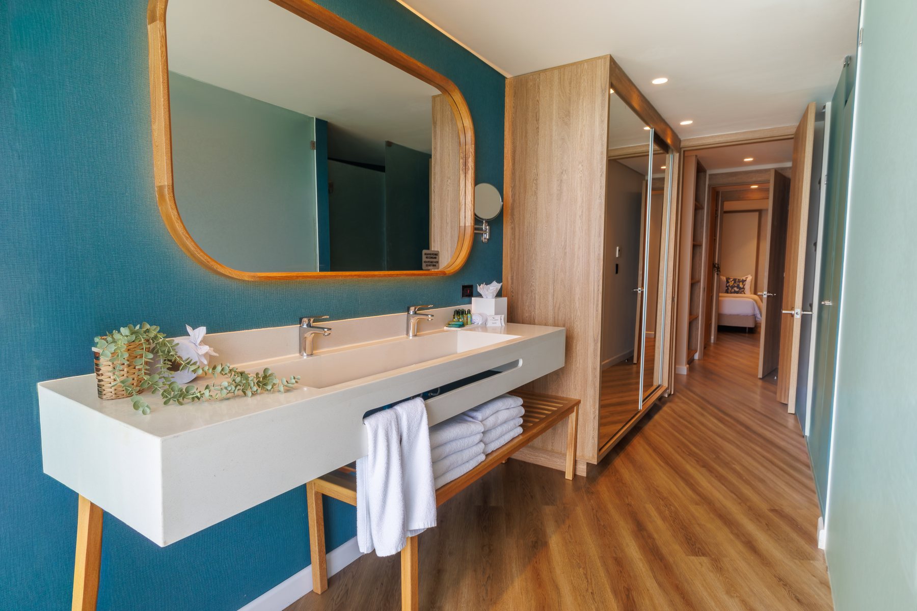 Baño del Grand Sirenis San Andrés con espejo de madera y paredes azul petróleo