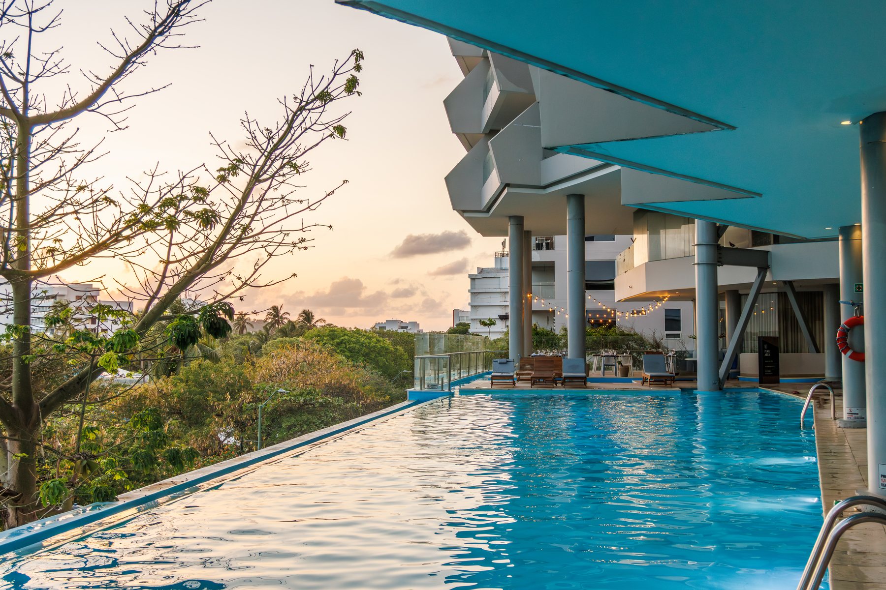 Piscina del Grand Sirenis San Andrés al atardecer, con el cielo naranja y la vegetación de la isla