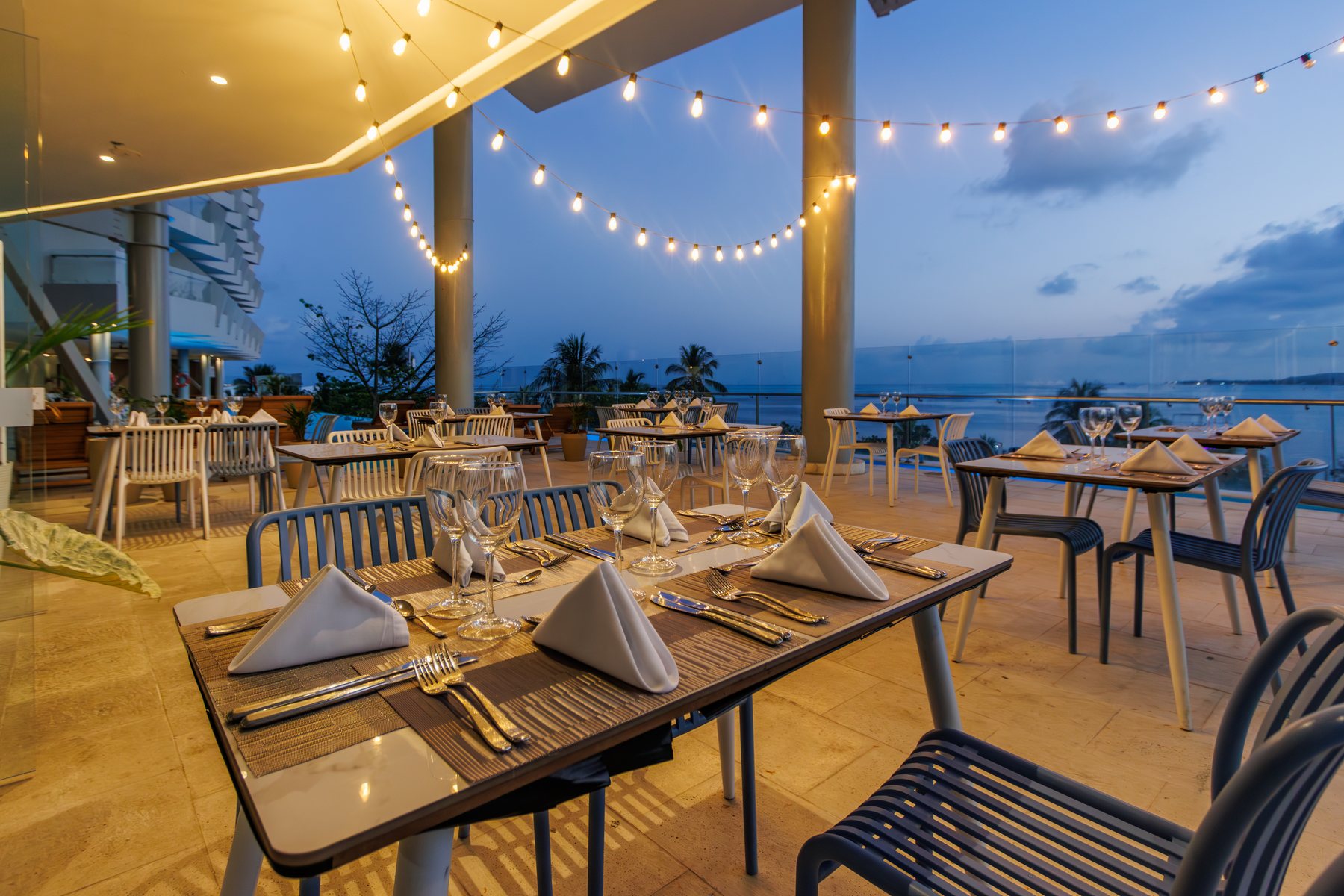 Terraza del restaurante con luces colgantes y el mar al fondo