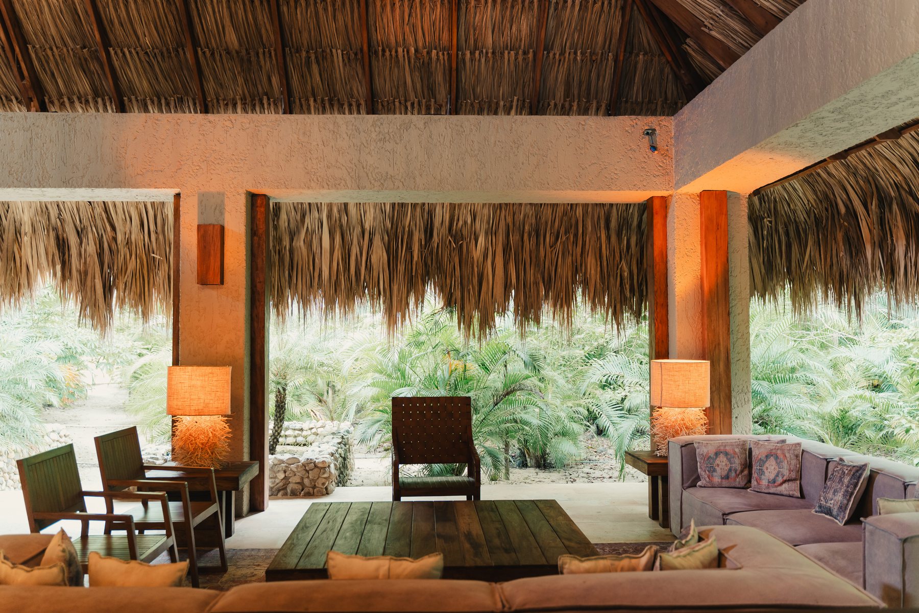 Lobby de Naio con techo de palma, lámparas y vista al jardín