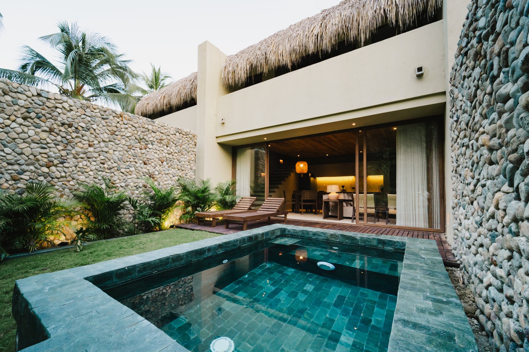 Villa de Naio con piscina privada de azulejo verde y muros de piedra de río