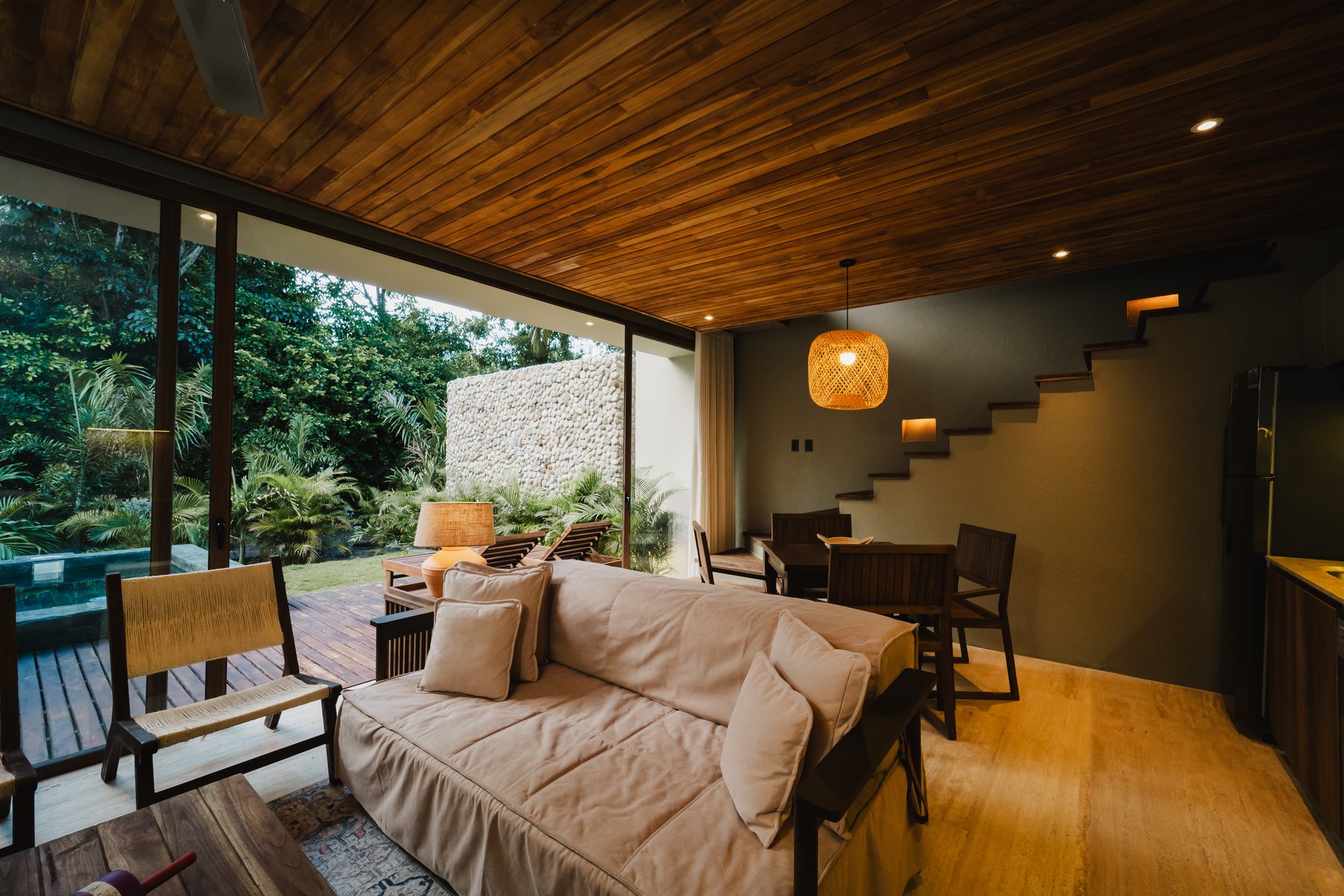 Sala de una villa de Naio con sofá, comedor y ventanal al jardín