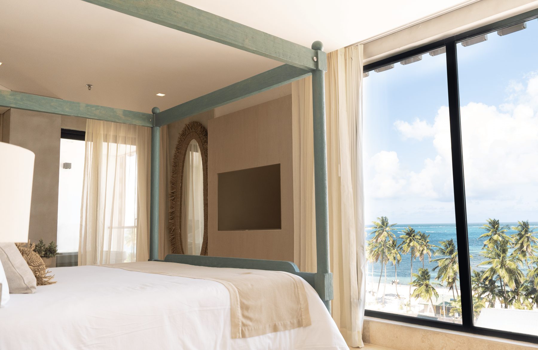Master Suite de Nattivo con cama de dosel y ventanal con palmeras y mar turquesa