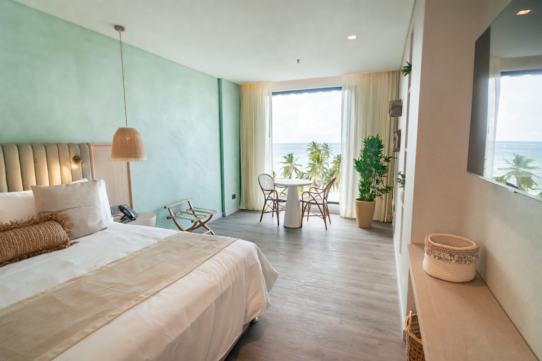 Habitación Superior de Nattivo con cama king, pared verde agua y ventanal al mar