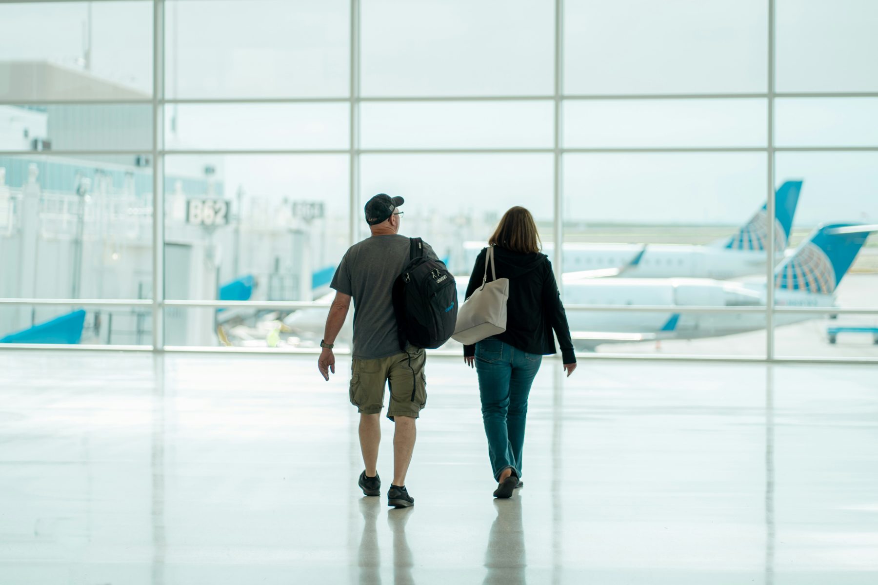 Pareja de viajeros caminando hacia la sala de abordaje en un aeropuerto